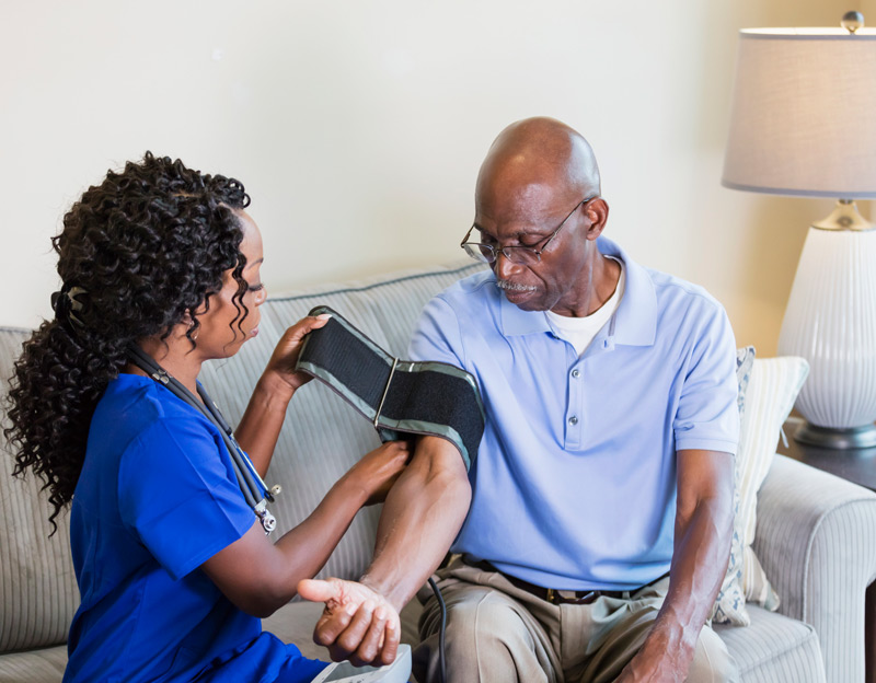 Home-health-aide-checking-senior-man’s-blood-pressure